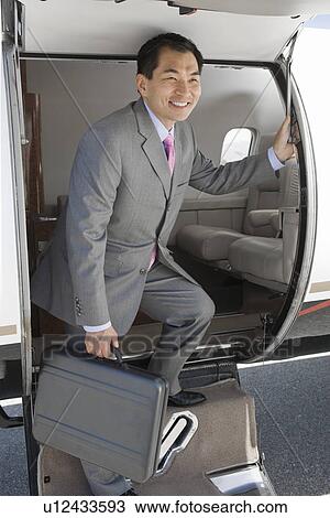 Stock Image - Asian businessman getting off airplane.. Fotosearch