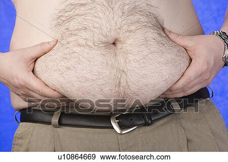 Stock Photo - Barechested pinching his belly, mid section. Fotosearch