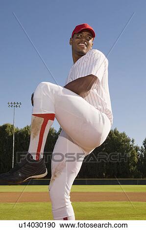 Stock Image - Baseball pitcher throwing ball during game. Fotosearch