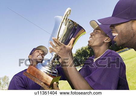 Baseball team mates with trophy, celebrating outdoors View Large Photo Image Picture - Baseball team mates with trophy, celebrating outdoors. Fotosearch