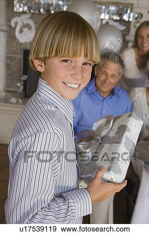 Stock Photo - Boy holding present, smiling. Fotosearch