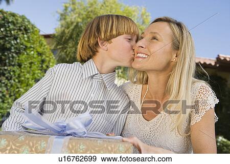 Boy kissing his mother on cheek and giving her birthday present View Large Photo Image Stock Photo - Boy kissing his mother on cheek and giving her birthday present. Fotosearch