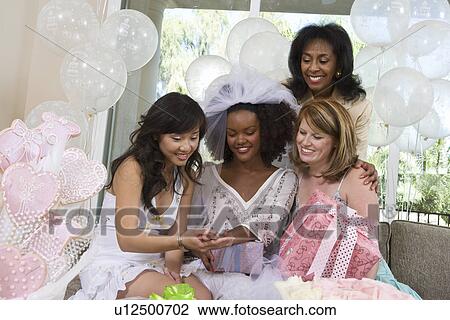 Stock Image - Bride showing engagement ring to friends at bridal shower. Fotosearch