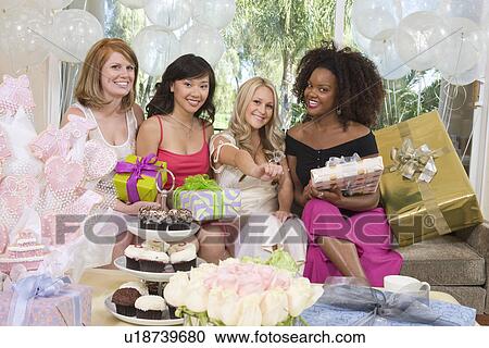 Stock Image - Bride sitting together with her Friends showing engagement ring at Bridal Shower. Fotosearch