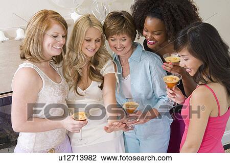 Stock Image - Bride standing together with friends watching her engagement ring. Fotosearch