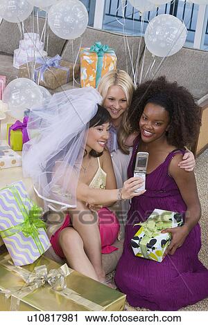 Bride with friends photographing themselves at bridal shower View Large Photo Image Stock Image - Bride with friends photographing themselves at bridal shower. Fotosearch