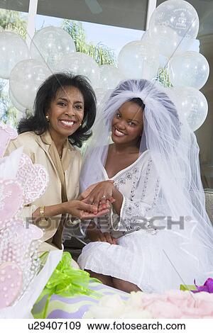 Stock Photo - Bride with mother showing her engagement ring at bridal shower. Fotosearch