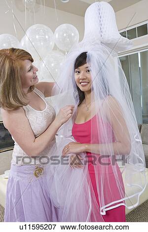 Bridesmaid adjusting bride's veil at bridal shower View Large Photo Image Stock Photo - Bridesmaid adjusting bride's veil at bridal shower. Fotosearch