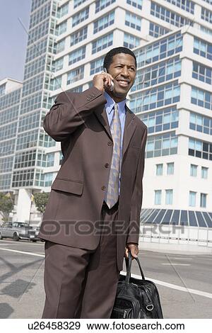Business man using mobile phone on city street View Large Photo Image Stock Photo - Business man using mobile phone on city street. Fotosearch