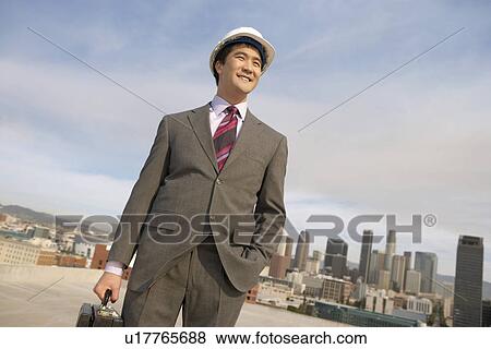 Business man wearing hard hat on city rooftop View Large Photo Image Stock Photo - Business man wearing hard hat on city rooftop. Fotosearch