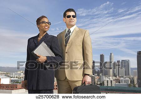 Stock Photo - Business people wearing sunglasses on city rooftop. Fotosearch