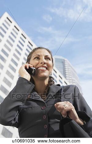 Stock Photography - Business woman using mobile phone on city street. Fotosearch