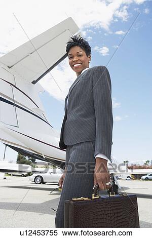 Stock Photography - Businesswoman Holding a Briefcase outside of airplane, low angle view. Fotosearch