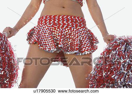 Stock Image - Cheerleader in costume with pom poms, mid section. Fotosearch