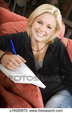 Stock Image - College student on couch making notes. Fotosearch