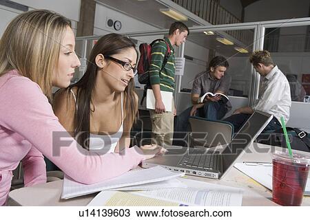 Stock Image - College students studying together on laptop in common room. Fotosearch