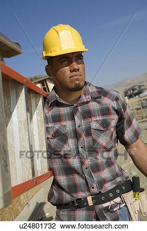 Construction worker carrying step ladder on construction site View Large Photo Image Stock Image - Construction worker carrying step ladder on construction site. Fotosearch
