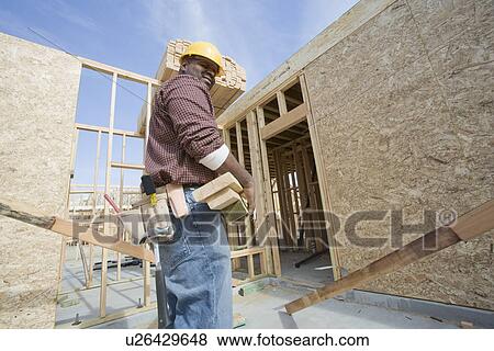 Construction worker carrying wooden plank View Large Photo Image Stock Photo - Construction worker carrying wooden plank. Fotosearch