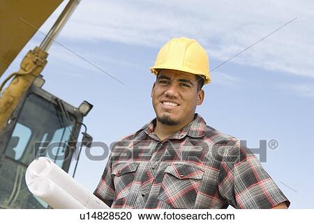 Stock Image - Construction worker holding blueprints, portrait. Fotosearch
