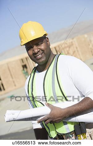 Stock Image - Construction worker holding blueprints. Fotosearch