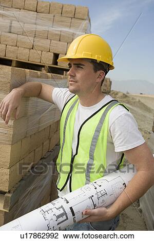 Construction worker holding blueprints on site View Large Photo Image Stock Image - Construction worker holding blueprints on site. Fotosearch