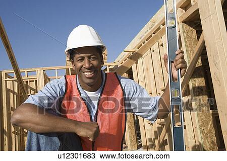 Construction worker holding spirit level on construction site View Large Photo Image Stock Image - Construction worker holding spirit level on construction site. Fotosearch