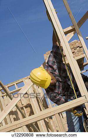 Construction worker measuring building View Large Photo Image Stock Photo - Construction worker measuring building. Fotosearch