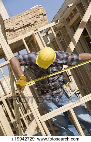 Stock Photo - Construction worker measuring building. Fotosearch