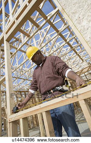 Construction worker measuring building View Large Photo Image Stock Photograph - Construction worker measuring building. Fotosearch