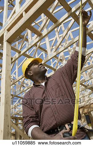 Stock Photography - Construction worker measuring building. Fotosearch