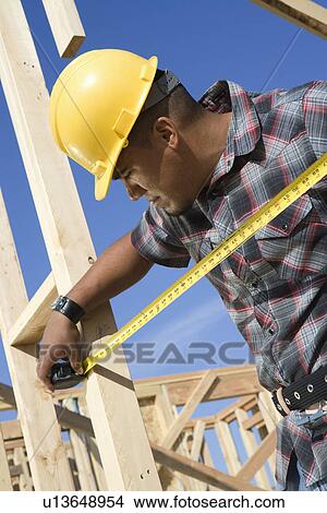 Construction worker measuring half constructed wall with tape measure View Large Photo Image Picture - Construction worker measuring half constructed wall with tape measure. Fotosearch