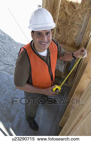 Construction worker measuring wall with measure taper inside half constructed house View Large Photo Image Stock Photography - Construction worker measuring wall with measure taper inside half constructed house. Fotosearch