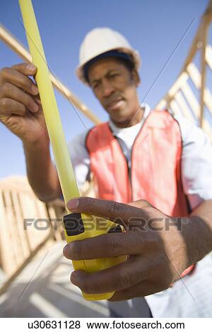 Construction worker measuring with tape measure View Large Photo Image Stock Photo - Construction worker measuring with tape measure. Fotosearch