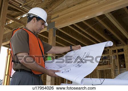 Construction worker observing half constructed house while holding blueprints View Large Photo Image Stock Photograph - Construction worker observing half constructed house while holding blueprints. Fotosearch