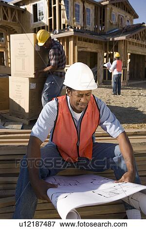 Stock Photo - Construction worker showing direction to another worker steering vehicle. Fotosearch
