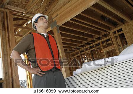 Construction Worker standing, hands on hip, on construction Site View Large Photo Image Stock Photo - Construction Worker standing, hands on hip, on construction Site. Fotosearch