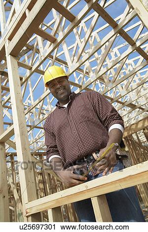 Construction Worker standing, holding tape measure on construction Site View Large Photo Image Stock Image - Construction Worker standing, holding tape measure on construction Site. Fotosearch