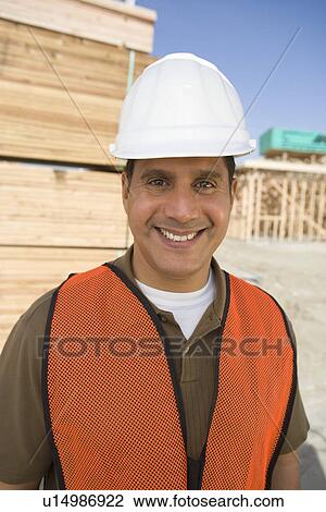 Stock Image - Construction worker standing on construction site. Fotosearch