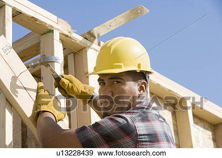 Construction worker using hammer on building View Large Photo Image Stock Photo - Construction worker using hammer on building. Fotosearch