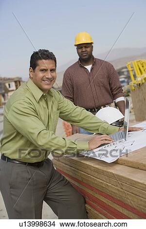 Construction worker using laptop, portrait View Large Photo Image Picture - Construction worker using laptop, portrait. Fotosearch