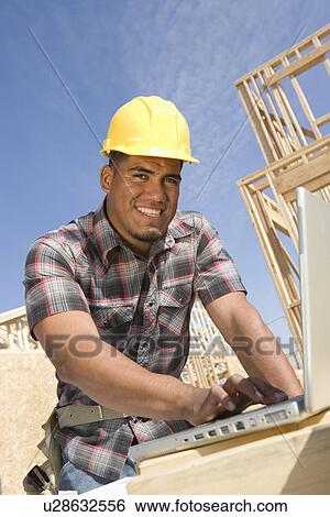 Stock Photograph - Construction worker using laptop. Fotosearch