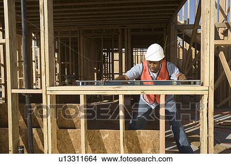 Picture - Construction worker using spirit level on construction site. Fotosearch