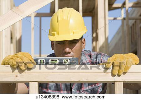 Stock Photo - Construction worker using spirit level on building. Fotosearch