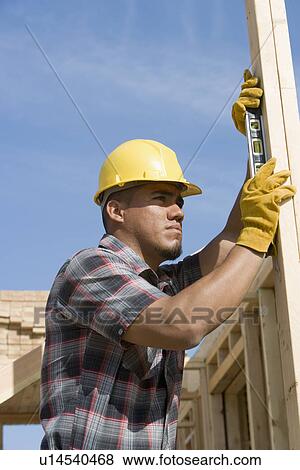 Construction worker using spirit level on building View Large Photo Image Stock Photo - Construction worker using spirit level on building. Fotosearch