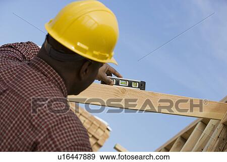 Stock Photo - Construction worker using spirit level on building. Fotosearch
