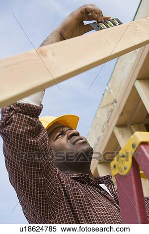 Stock Photography - Construction worker using spirit level on building. Fotosearch