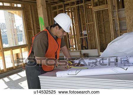 Construction worker using tape measure inside half constructed house View Large Photo Image Stock Photography - Construction worker using tape measure inside half constructed house. Fotosearch