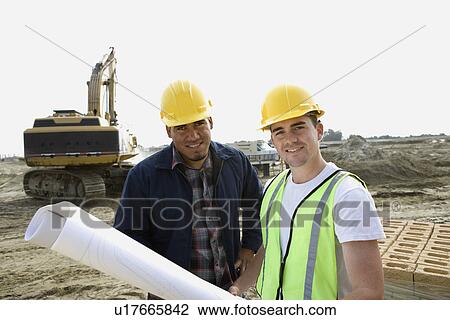 Stock Image - Construction workers with blueprints on site, portrait. Fotosearch