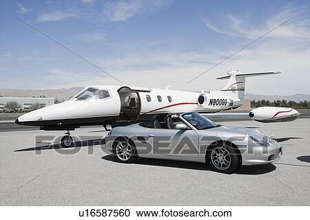 Stock Image - Convertible and private jet on landing strip.. Fotosearch