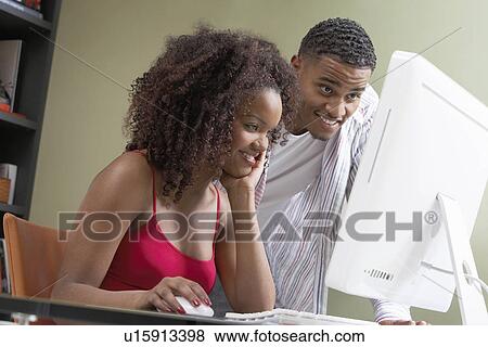 Stock Photo - Couple at desk looking at computer screen. Fotosearch